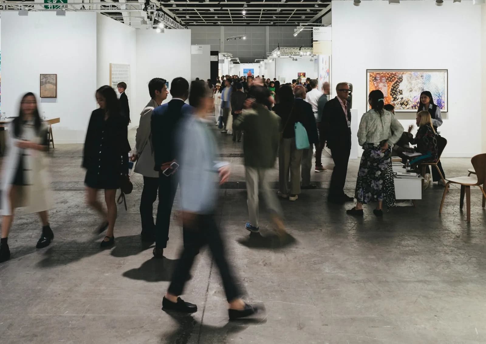 A gallery staff member arranging paintings inside a crowded art fair booth before opening day.